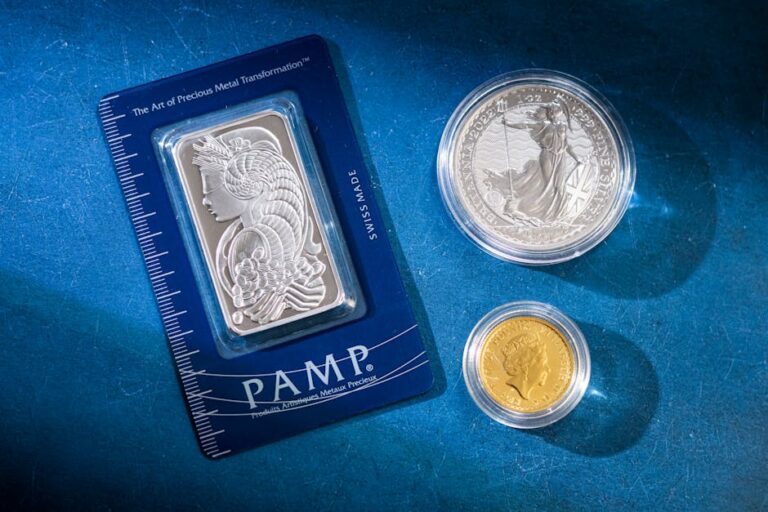 Silver bar and coins on blue surface, highlighting investment and collectible value.